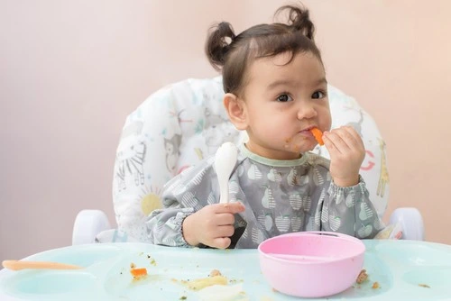 Bayi sedang memegang makanannya. Bayi sedang memegang makanannya.