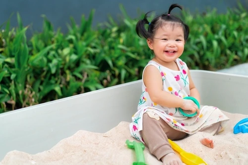Anak perempuan bermain pasir.
